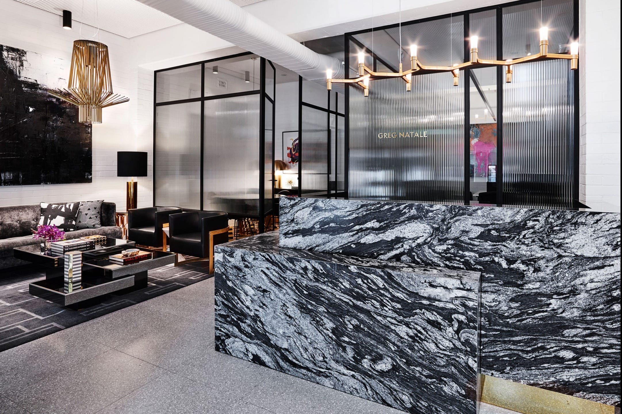 Modern office lobby with stylish black and gray marble reception desk, elegant furnishings, and artistic decor.