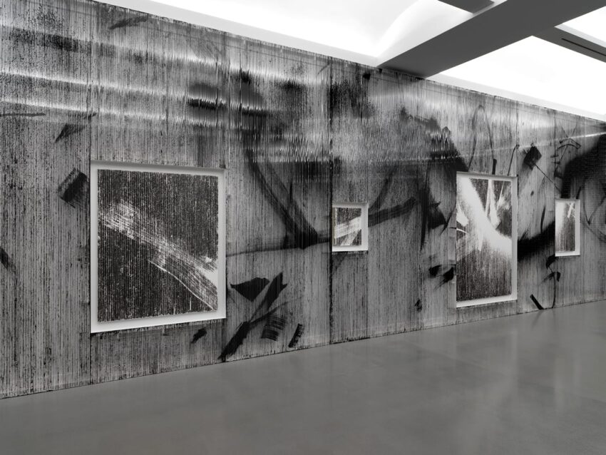 Art gallery with abstract black and white paintings on a textured wall, under bright overhead lighting.