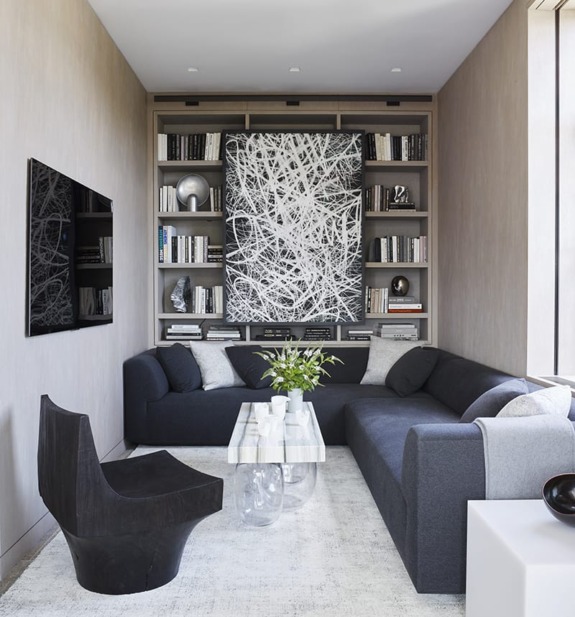 Modern living room with sectional sofa, abstract art, bookshelves, and a sleek black chair.