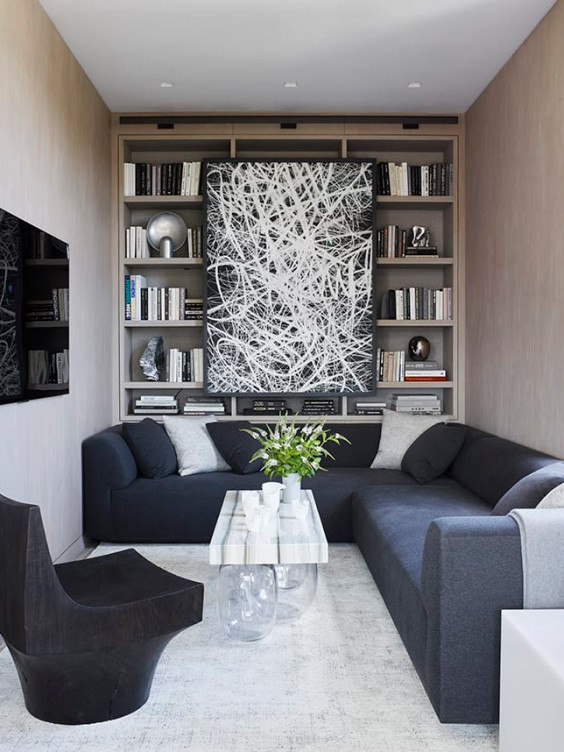 Modern living room with sectional sofa, abstract art, bookshelves, and a sleek black chair.