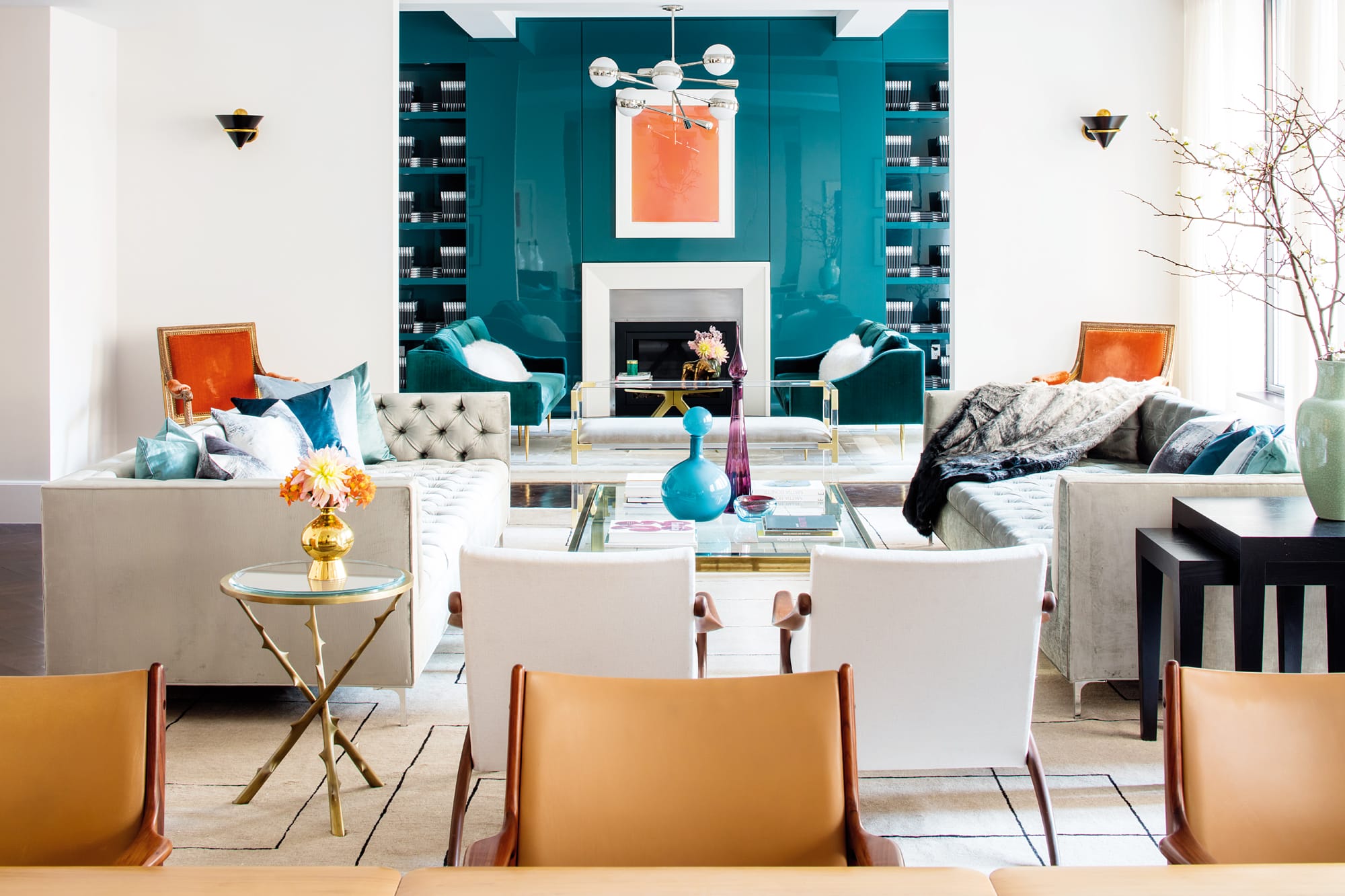 Contemporary living room with colorful chairs, modern decor, vibrant artwork, and natural light from large windows.