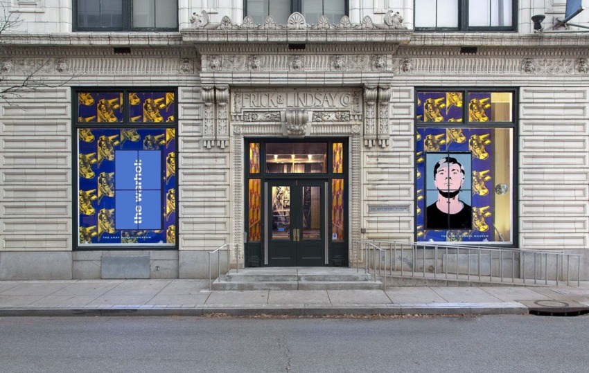Exterior of glass art gallery with colorful patterned window displays and ornate stone facade.