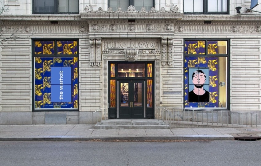 Exterior of glass art gallery with colorful patterned window displays and ornate stone facade.