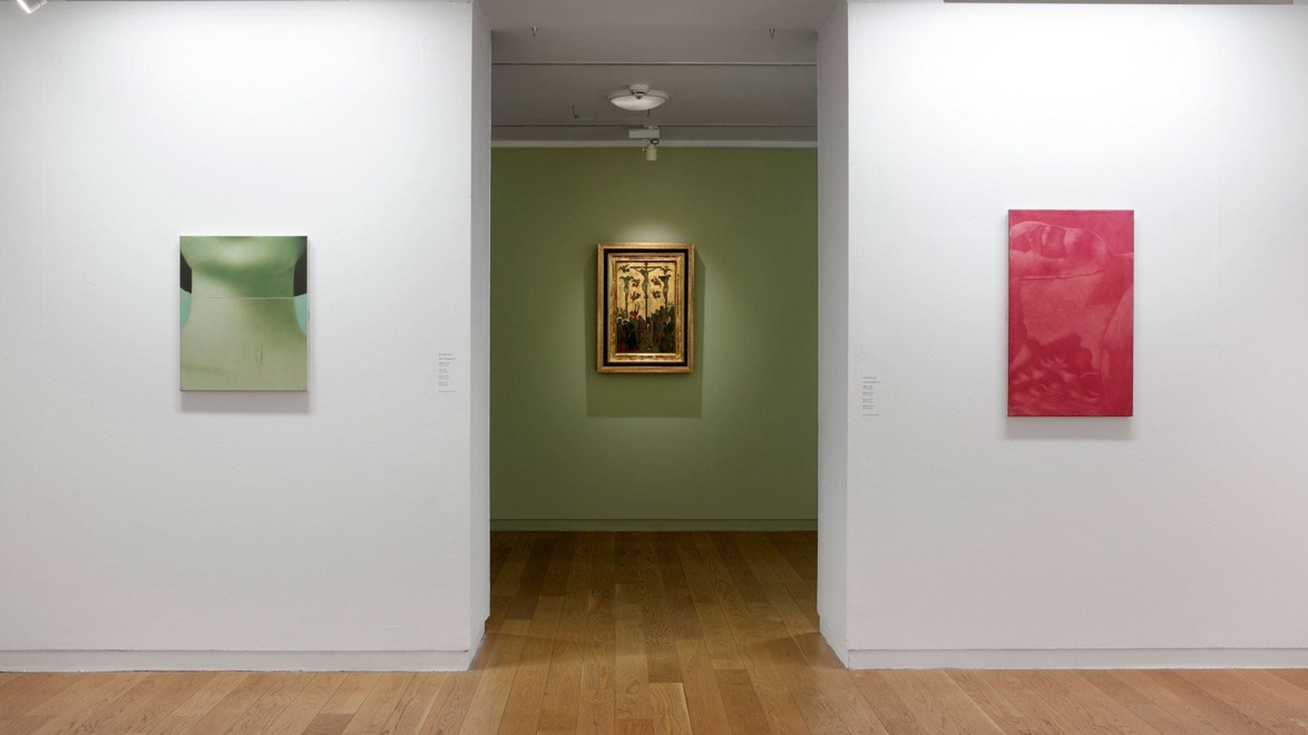 Art gallery with three paintings on display, one on each white wall and a centerpiece in a green room, wood flooring.