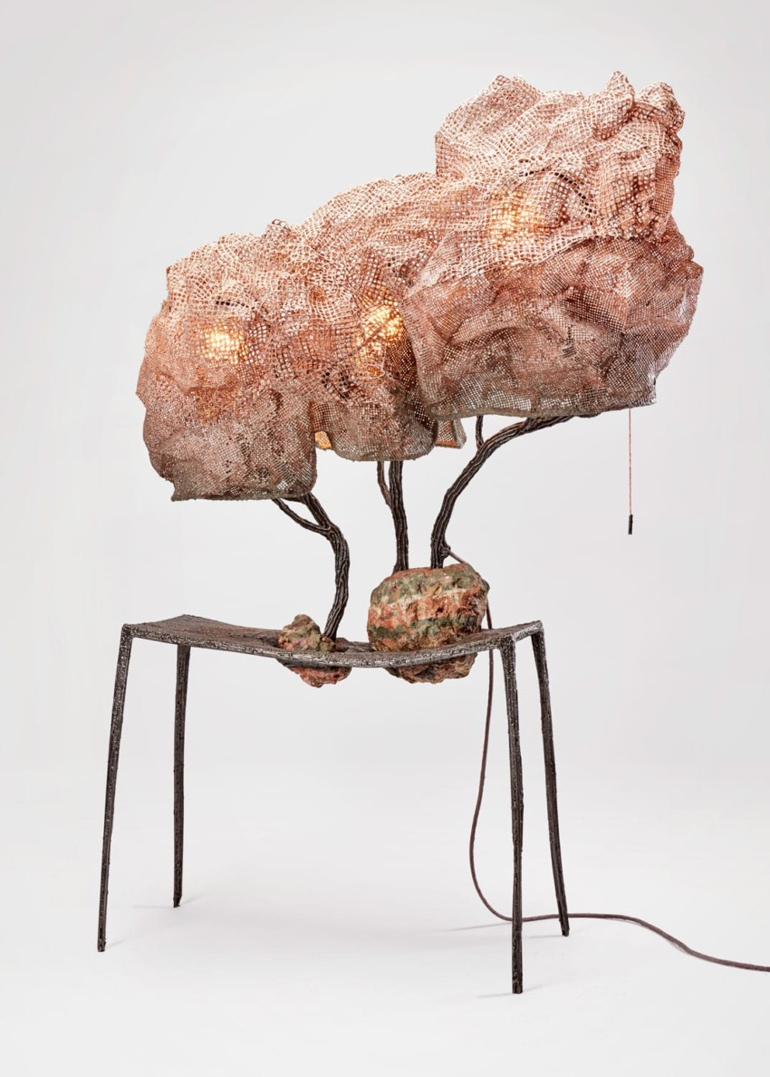 Sculptural table lamp with a complex copper mesh design and glowing bulbs, set on a minimalist metal base.