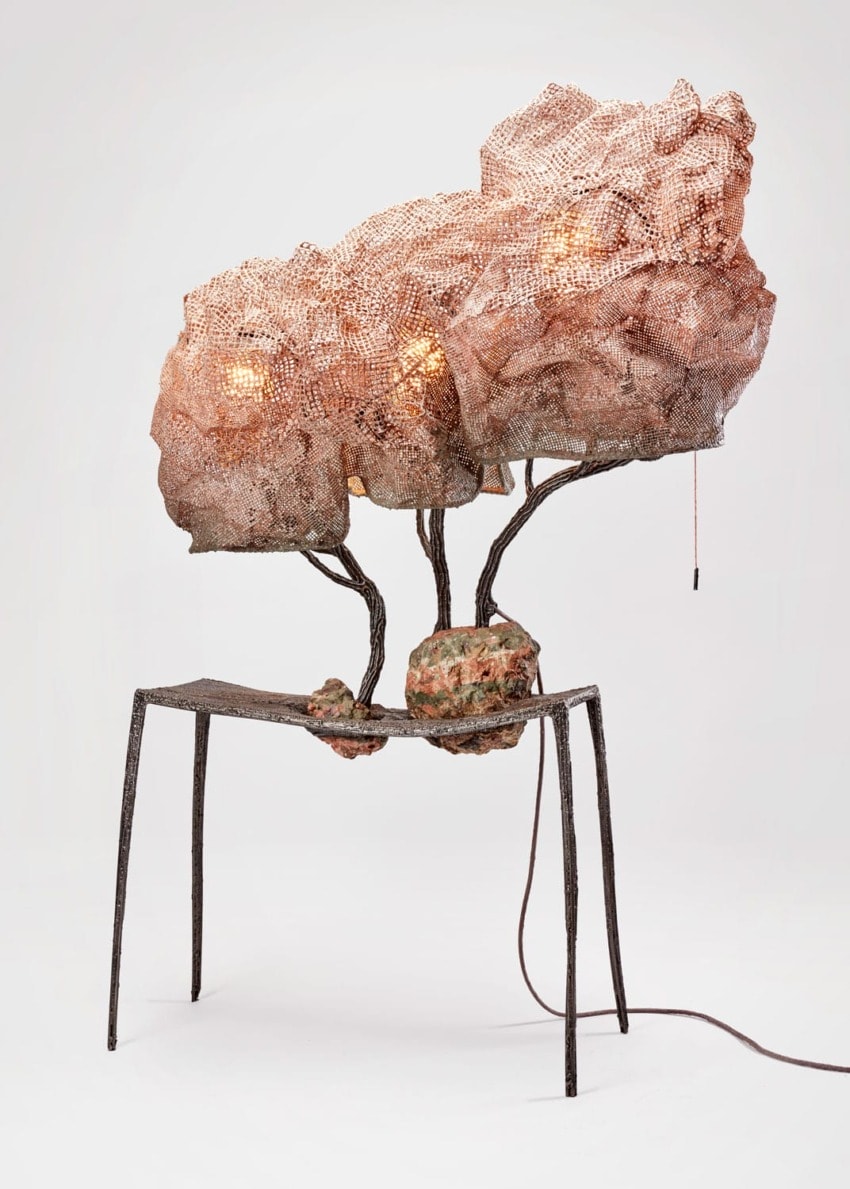 Sculptural table lamp with a complex copper mesh design and glowing bulbs, set on a minimalist metal base.