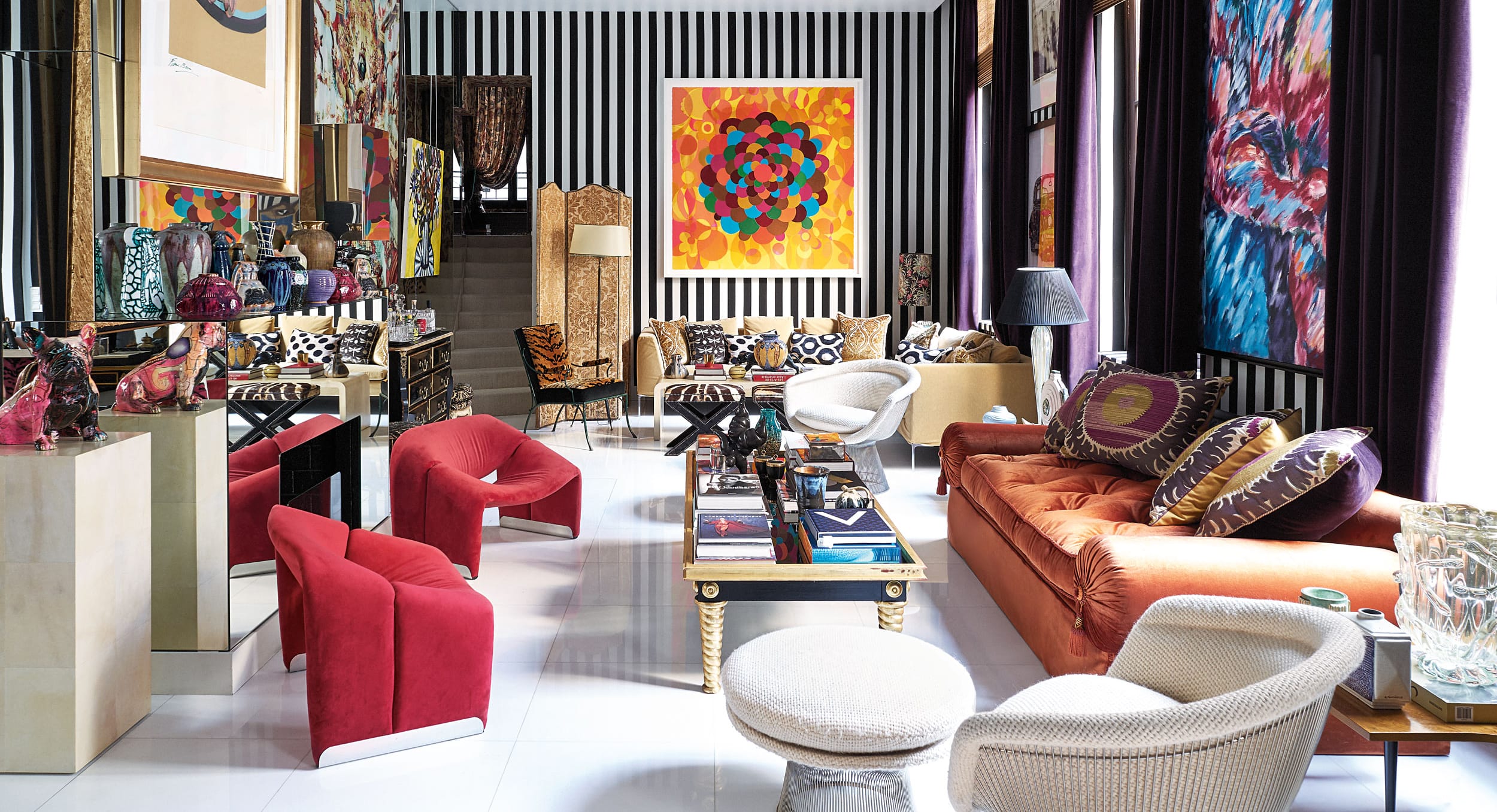 Colorful living room with striped walls, vibrant art, and eclectic furniture.
