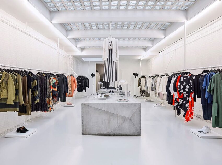 Modern clothing store interior with a variety of garments displayed on racks and a central concrete display table.