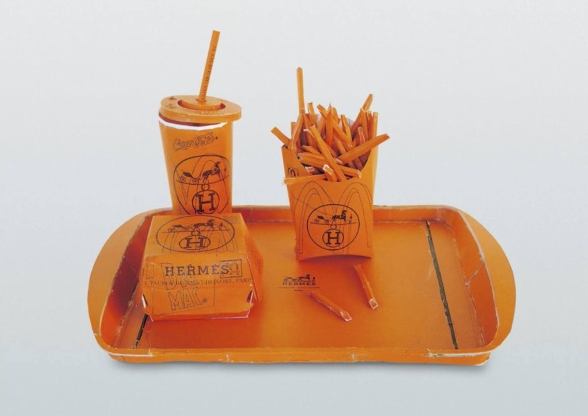 Fast food meal set made of orange Hermes packaging, including a burger box, fries container, and drink cup with straw.