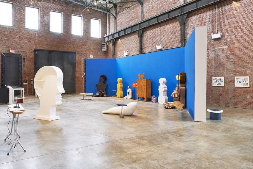 Contemporary art gallery with various abstract sculptures and installations in an industrial-style setting with brick walls.