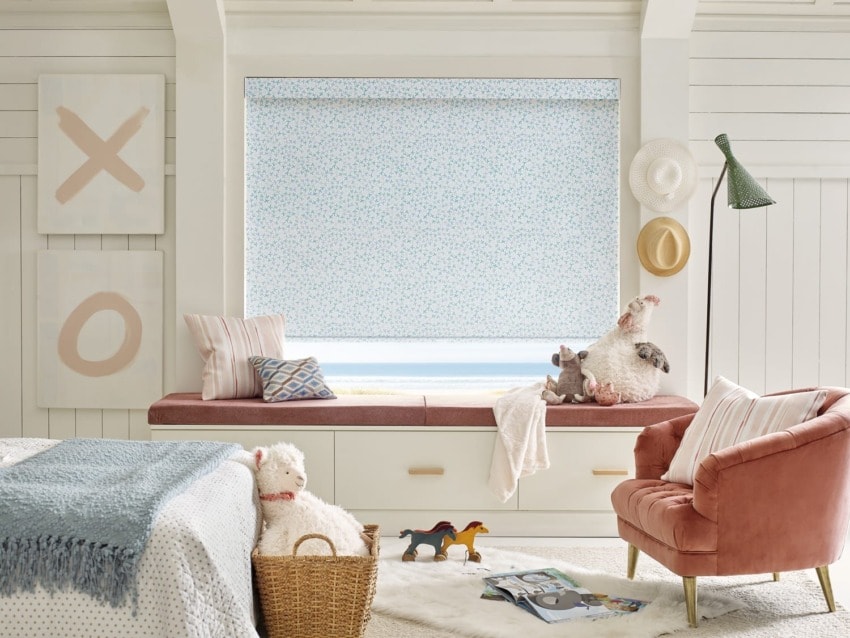Stylish cozy bedroom with a window seat, decorative pillows, stuffed animals, and a pink chair.