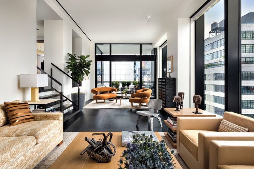 Modern living room with large windows, stylish furniture, plants, and city views, featuring a cozy seating area.