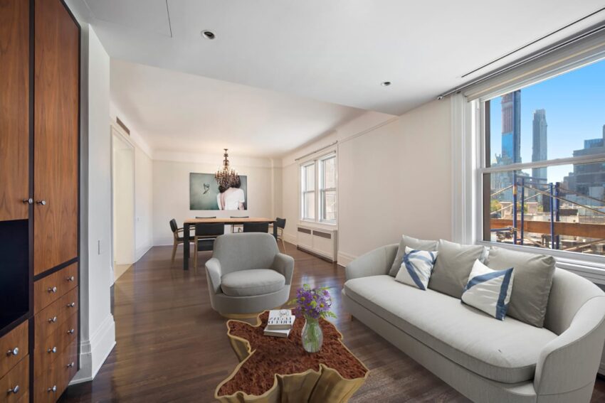 Modern living room with large windows, city view, gray sofa, armchair, coffee table, and dining area in the background.