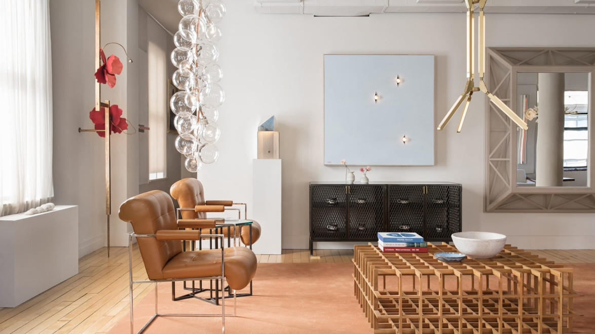 Modern living room with leather chairs, geometric wooden table, and abstract art on walls. Bright natural light fills the space.