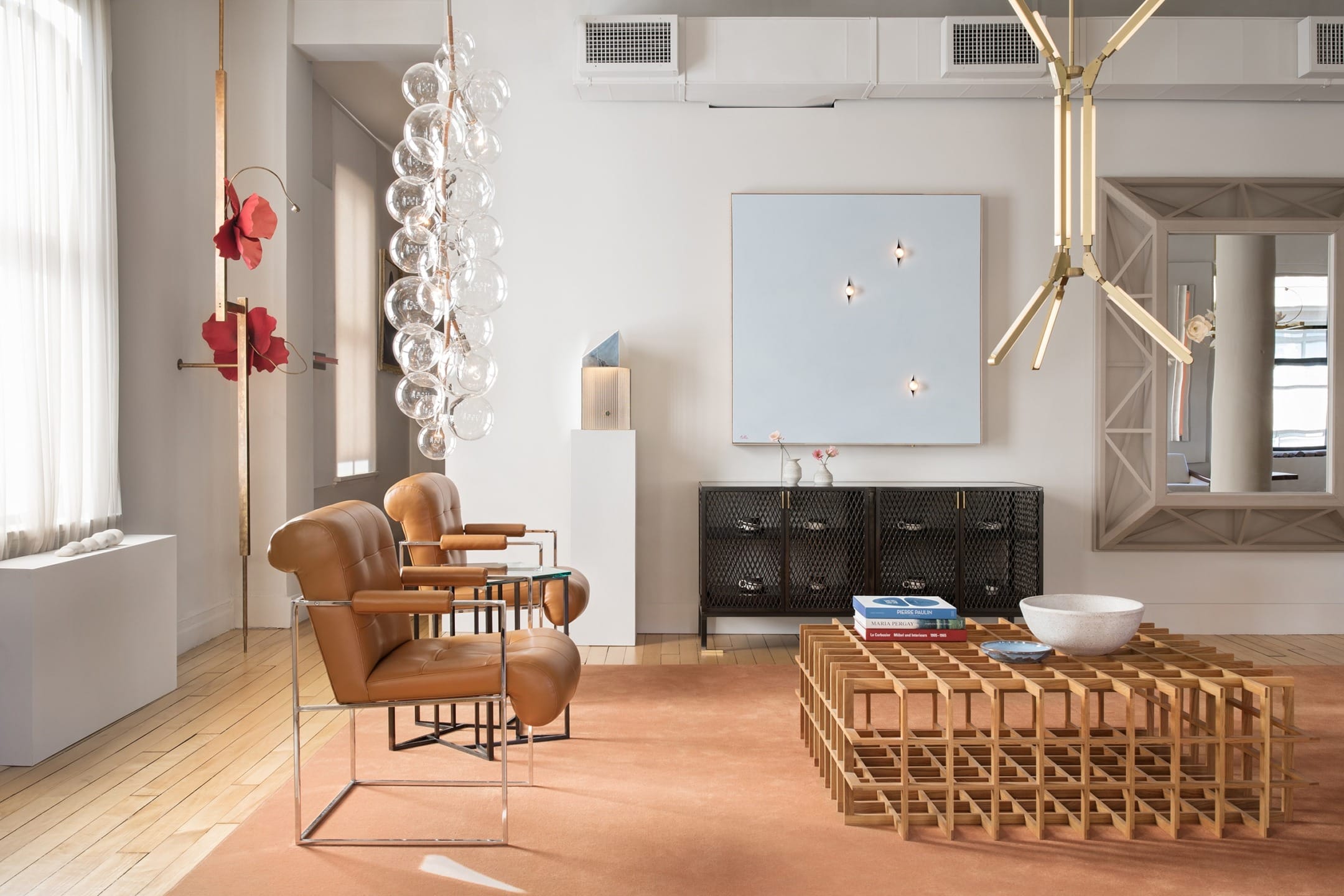 Modern living room with leather chairs, geometric wooden table, and abstract art on walls. Bright natural light fills the space.