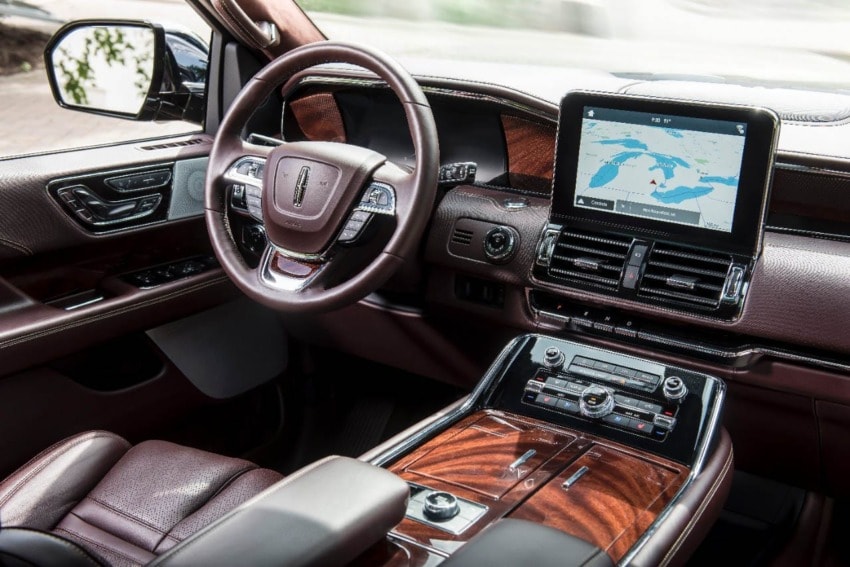 Luxury car interior featuring a modern dashboard, touchscreen display with map, and leather-wrapped steering wheel.