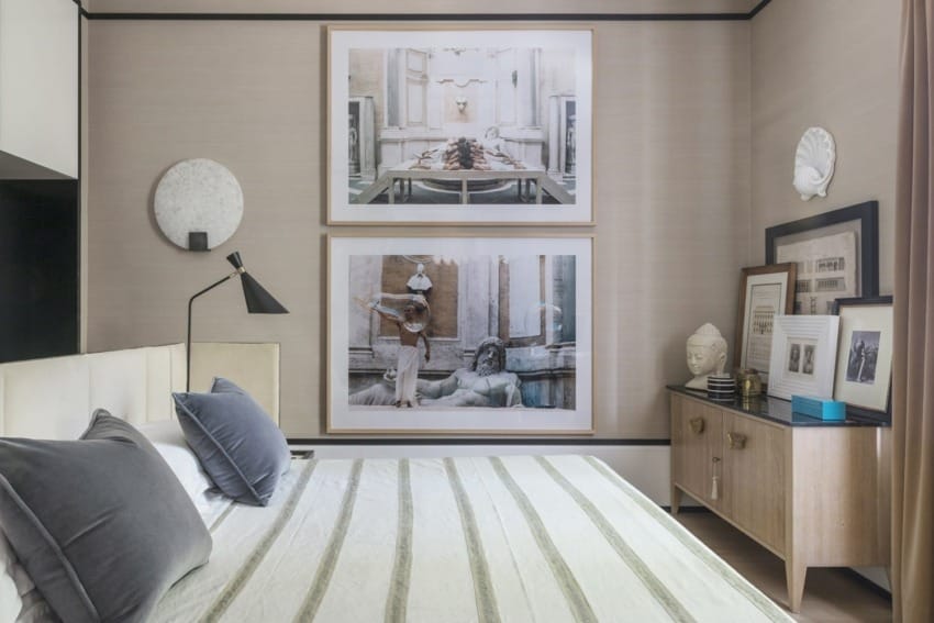 modern bedroom with two large framed art pieces above the bed, striped bedding, and a wooden sideboard with decor items