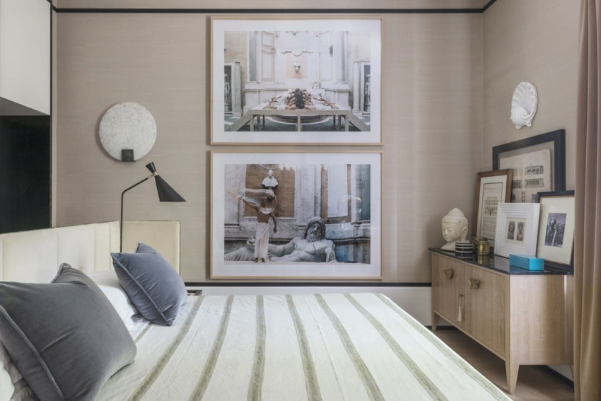 modern bedroom with two large framed art pieces above the bed, striped bedding, and a wooden sideboard with decor items