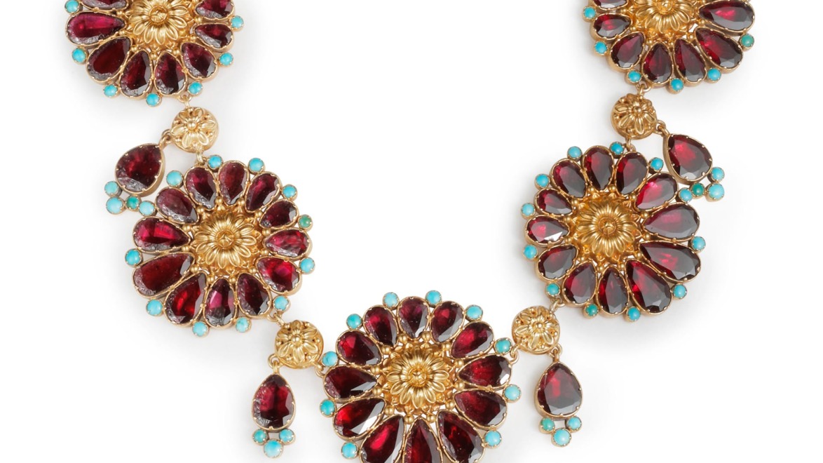 Gold floral necklace with red and turquoise gemstones arranged in an ornate, symmetrical design.