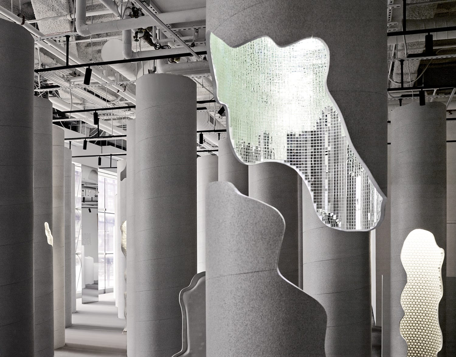 Modern architectural interior with cylindrical columns and reflective abstract installations.