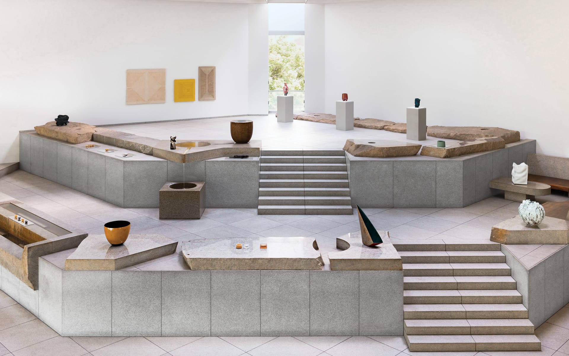 Modern art gallery with geometric stone displays, abstract sculptures, and a bright window view.