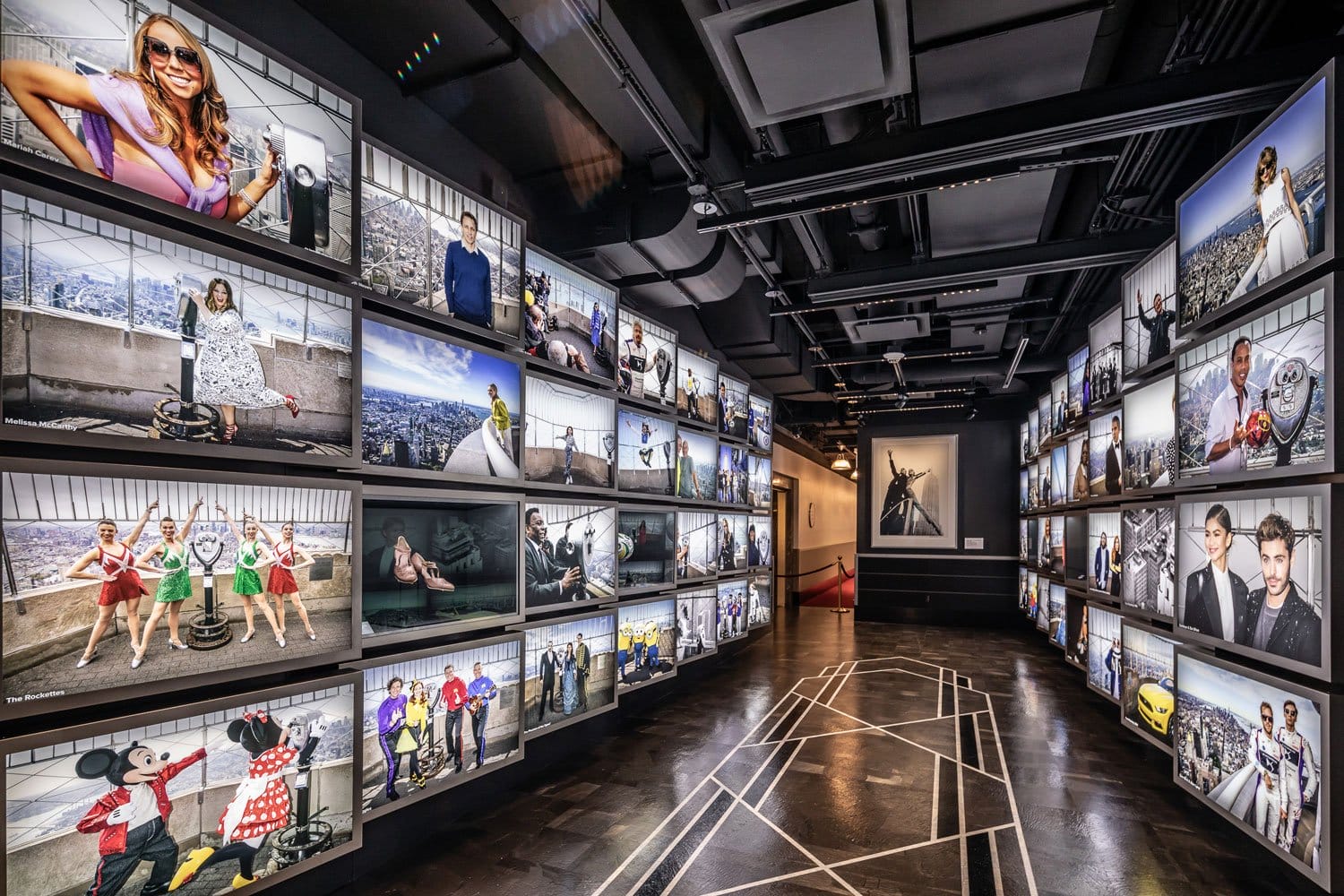 Hallway lined with photos of celebrities in various poses and outfits under modern lighting.