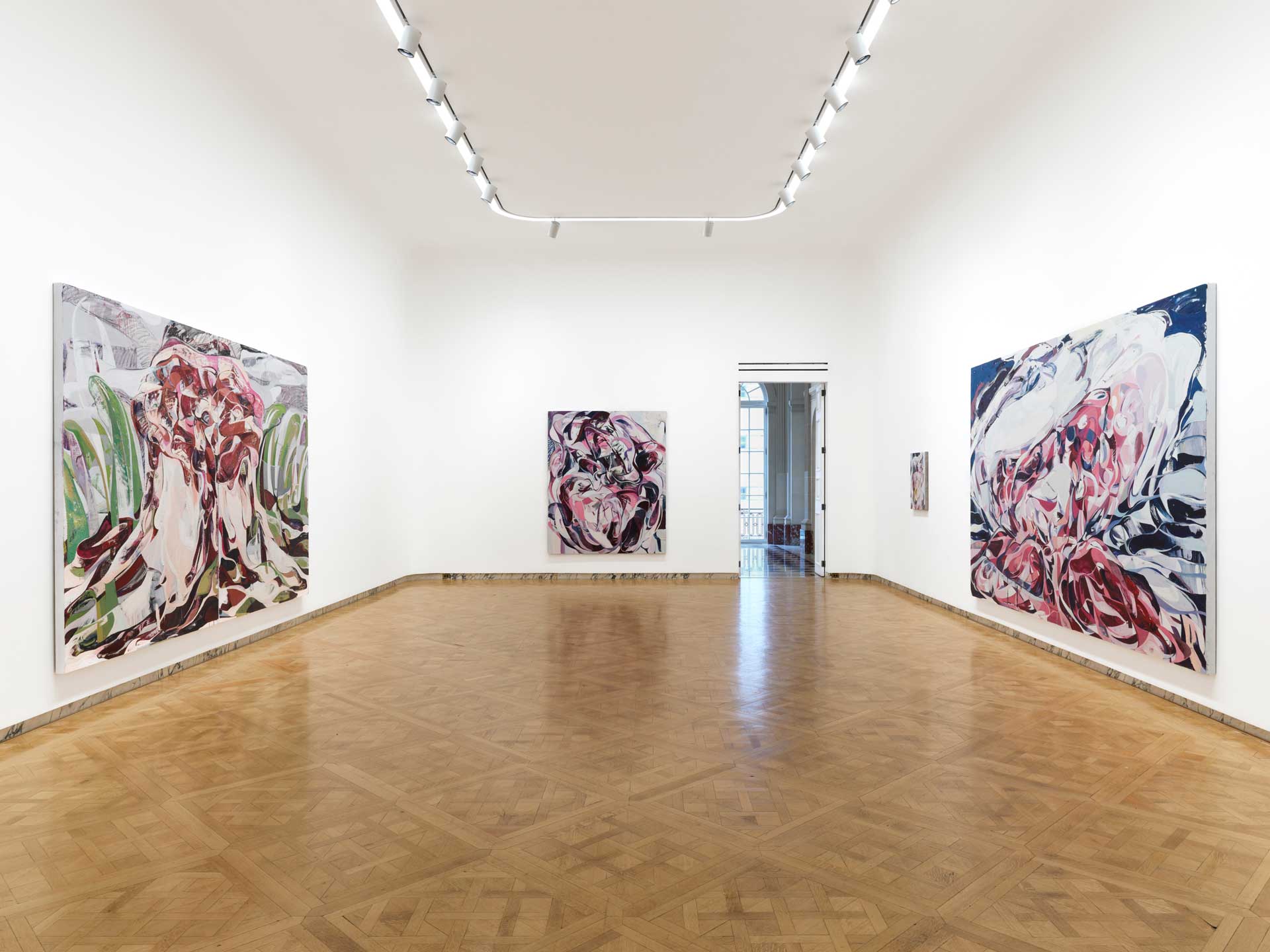 Art gallery room featuring three abstract paintings on white walls, with a wooden floor and ceiling lights.