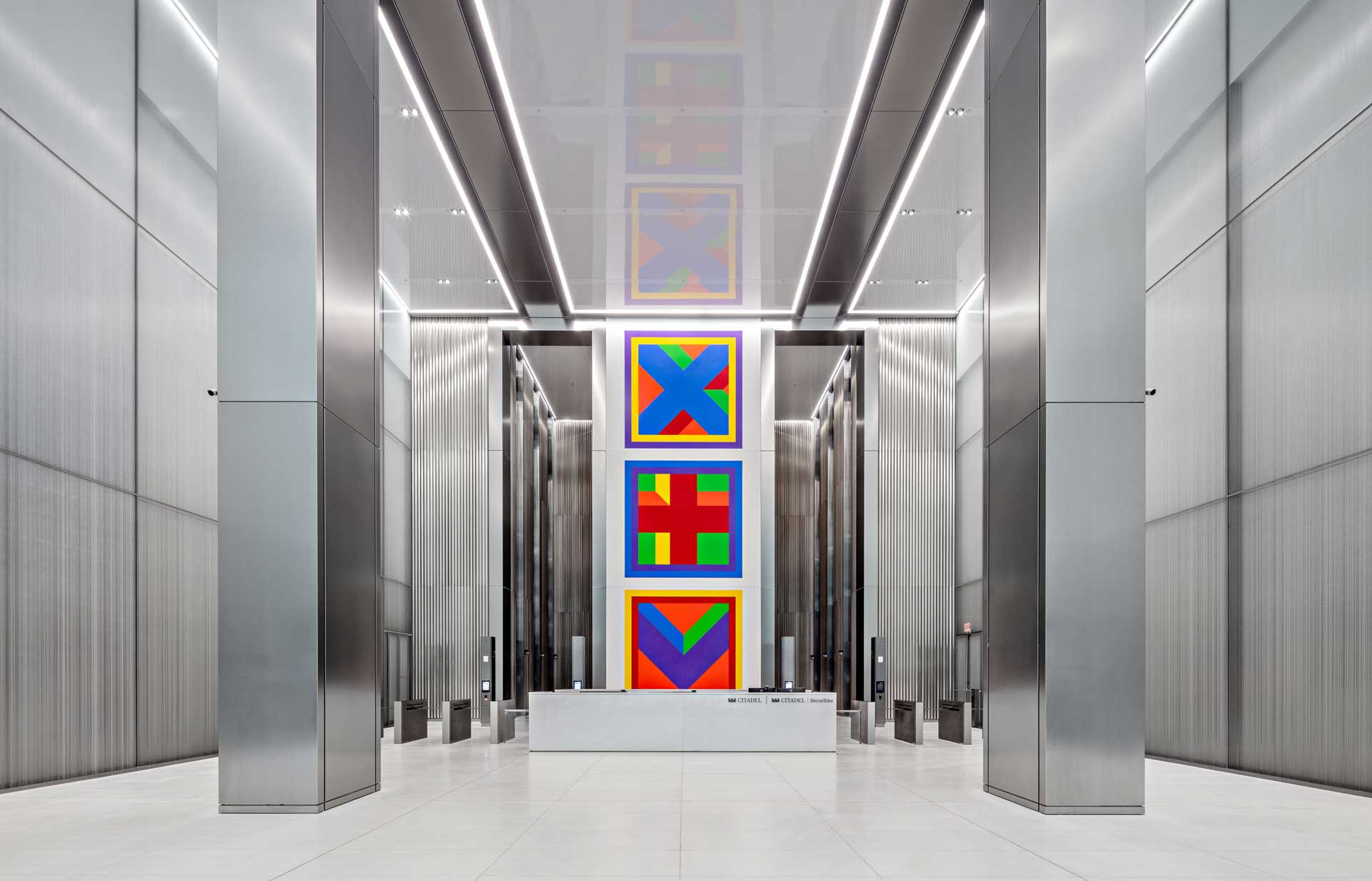 Modern lobby with high ceilings, metallic finishes, and colorful abstract art displayed on the wall.