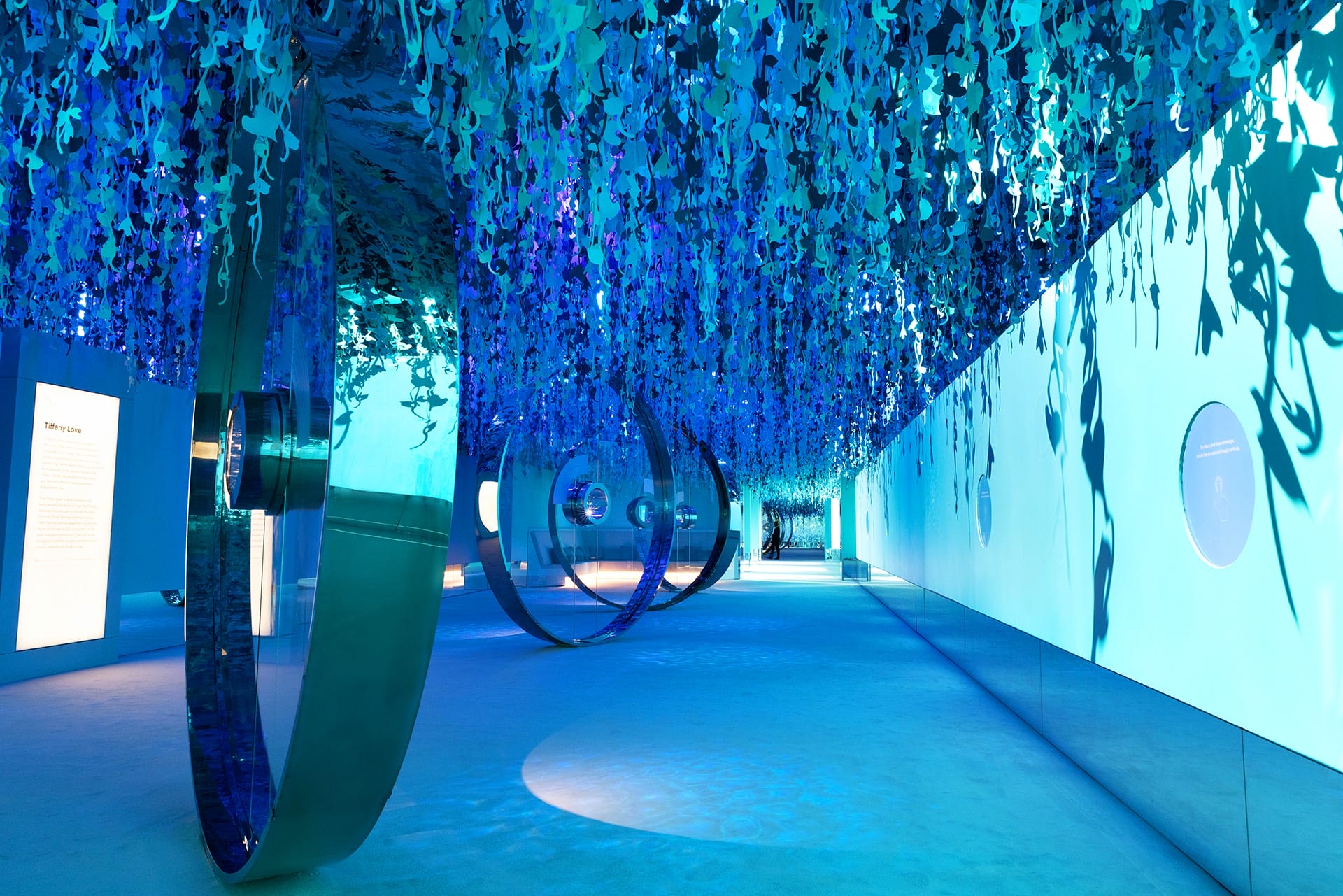 Futuristic room with blue lighting, reflective surfaces, and hanging decorations creating an immersive environment.