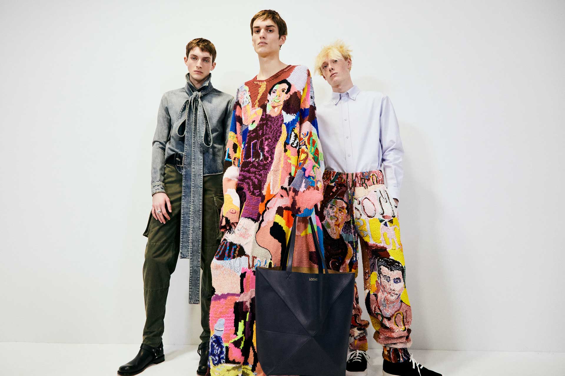 Three models wearing colorful, artistic outfits in a studio setting, showcasing modern fashion designs.