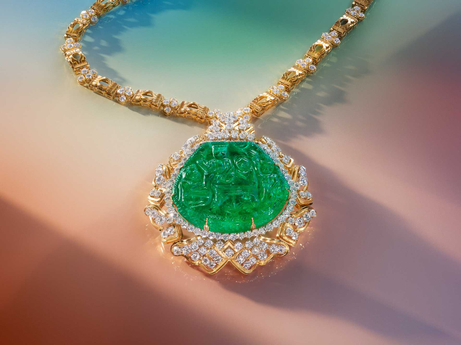 Gold and diamond necklace with large green gemstone pendant on a colorful gradient background.