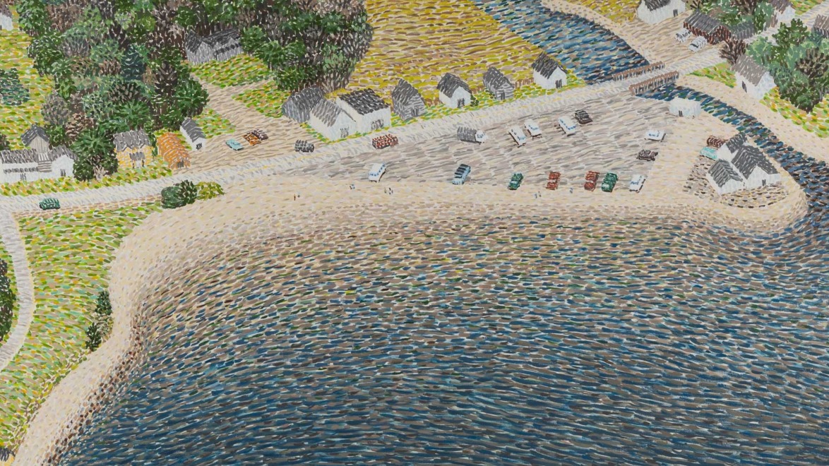 Aerial view of quaint seaside village with cottages, parked cars, sandy beach, and lush green trees by the water.