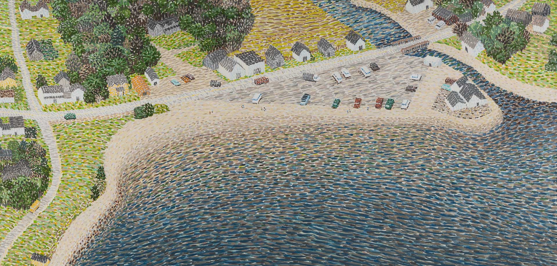 Aerial view of quaint seaside village with cottages, parked cars, sandy beach, and lush green trees by the water.