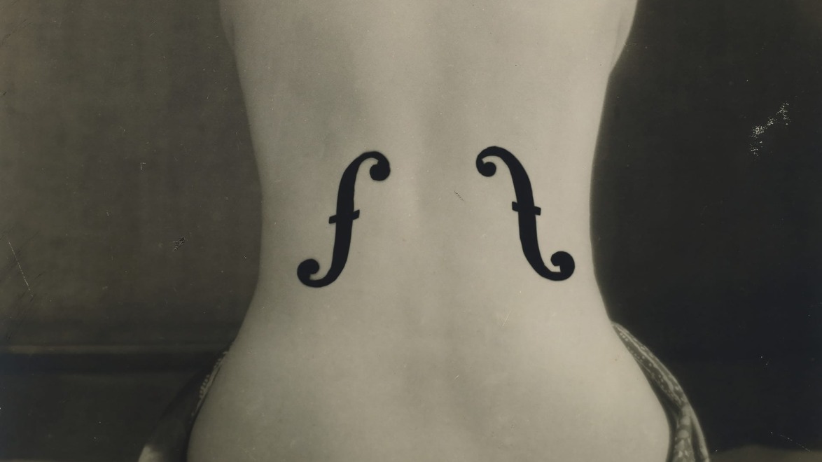 Artistic black and white photo of a woman's back with violin f-holes painted on it, resembling a musical instrument.