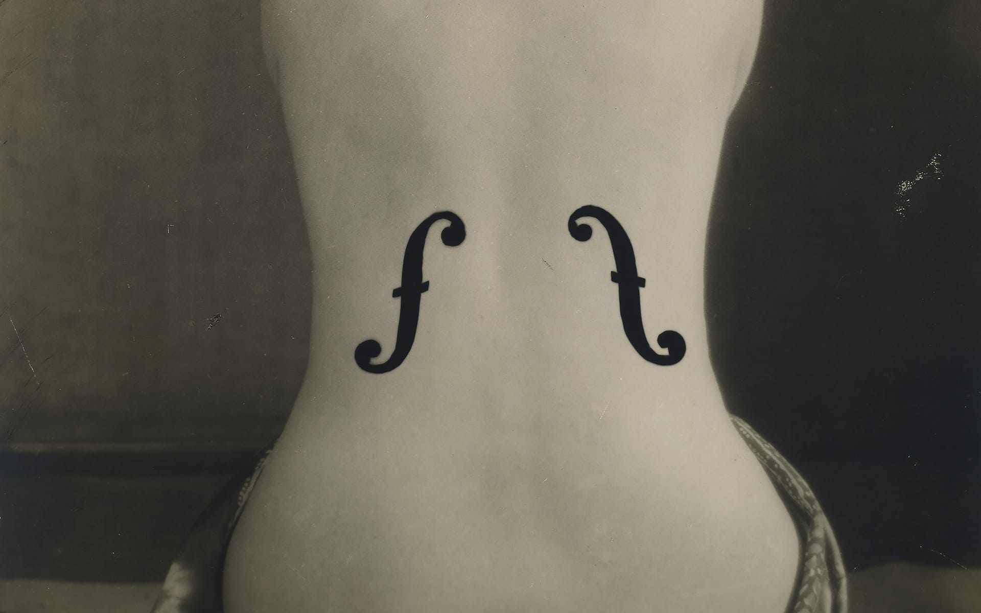 Artistic black and white photo of a woman's back with violin f-holes painted on it, resembling a musical instrument.