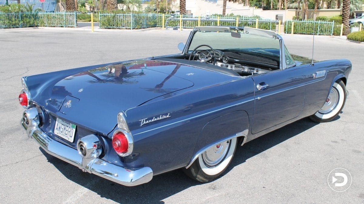 Blue vintage convertible car parked in a sunny lot with the top down and classic styling details.