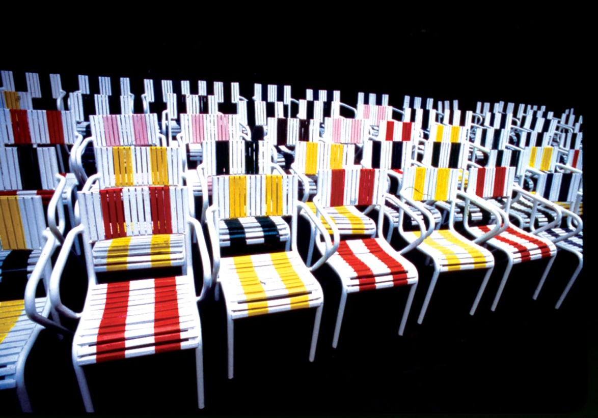 Rows of colorful striped chairs arranged in a pattern against a black background.