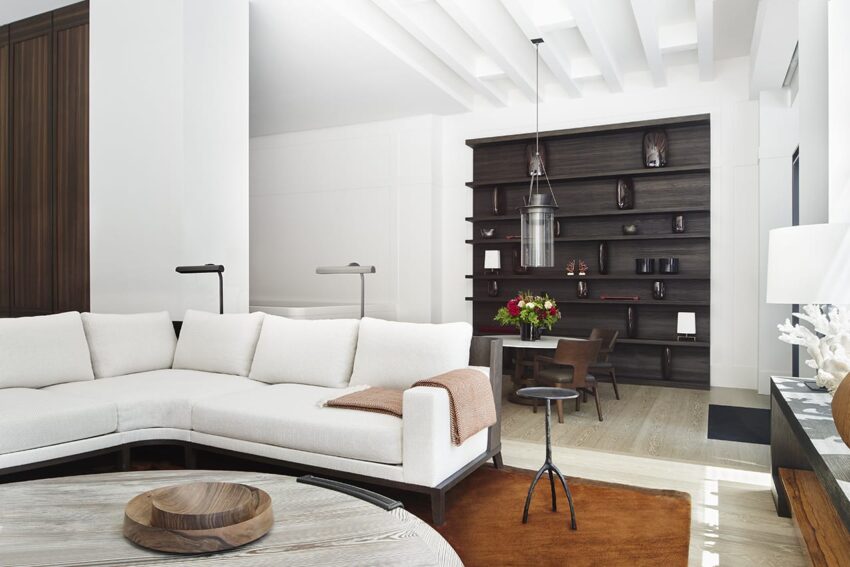 Modern living room with white sectional sofa, wooden shelves, and floor lamp, featuring a minimalist design.