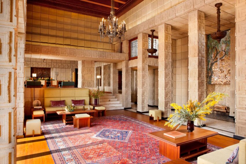 Art deco style interior with geometric patterns, colorful rugs, modern furniture, and a chandelier in an elegant room.