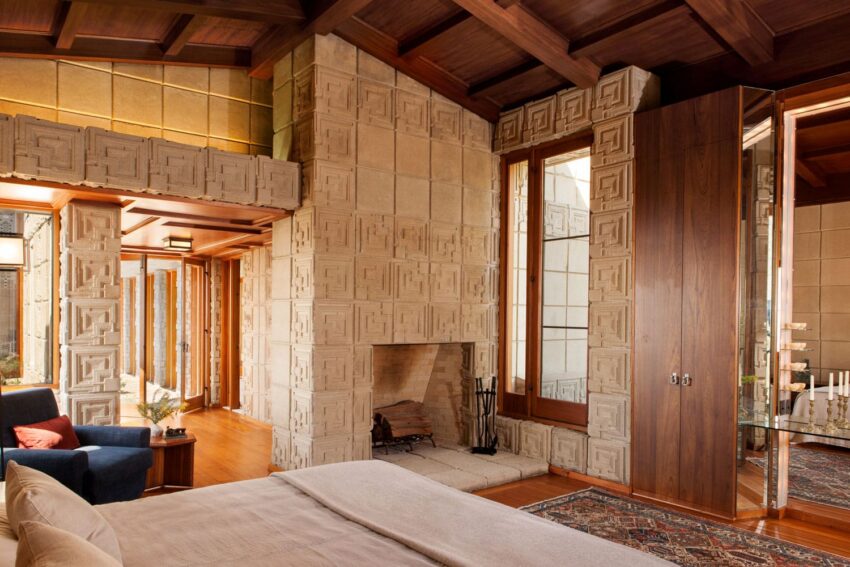 Cozy modern bedroom with geometric wall designs, wooden ceiling, fireplace, large windows, and a stylish rug.