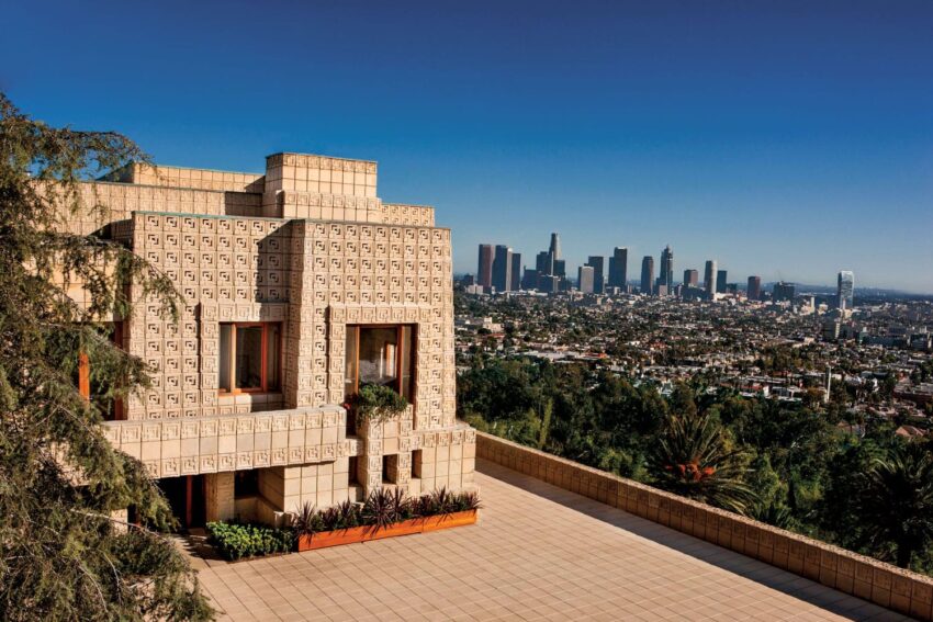 Frank Lloyd Wright's Ennis House with Los Angeles skyline in the background under a clear blue sky.