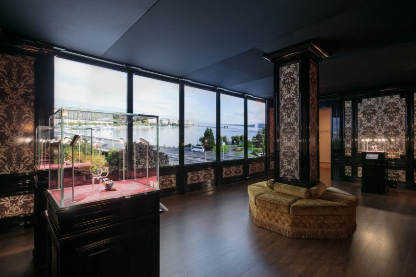 Luxurious room with elegant decor, large windows showcasing a waterfront view, and a display case with decorative items.