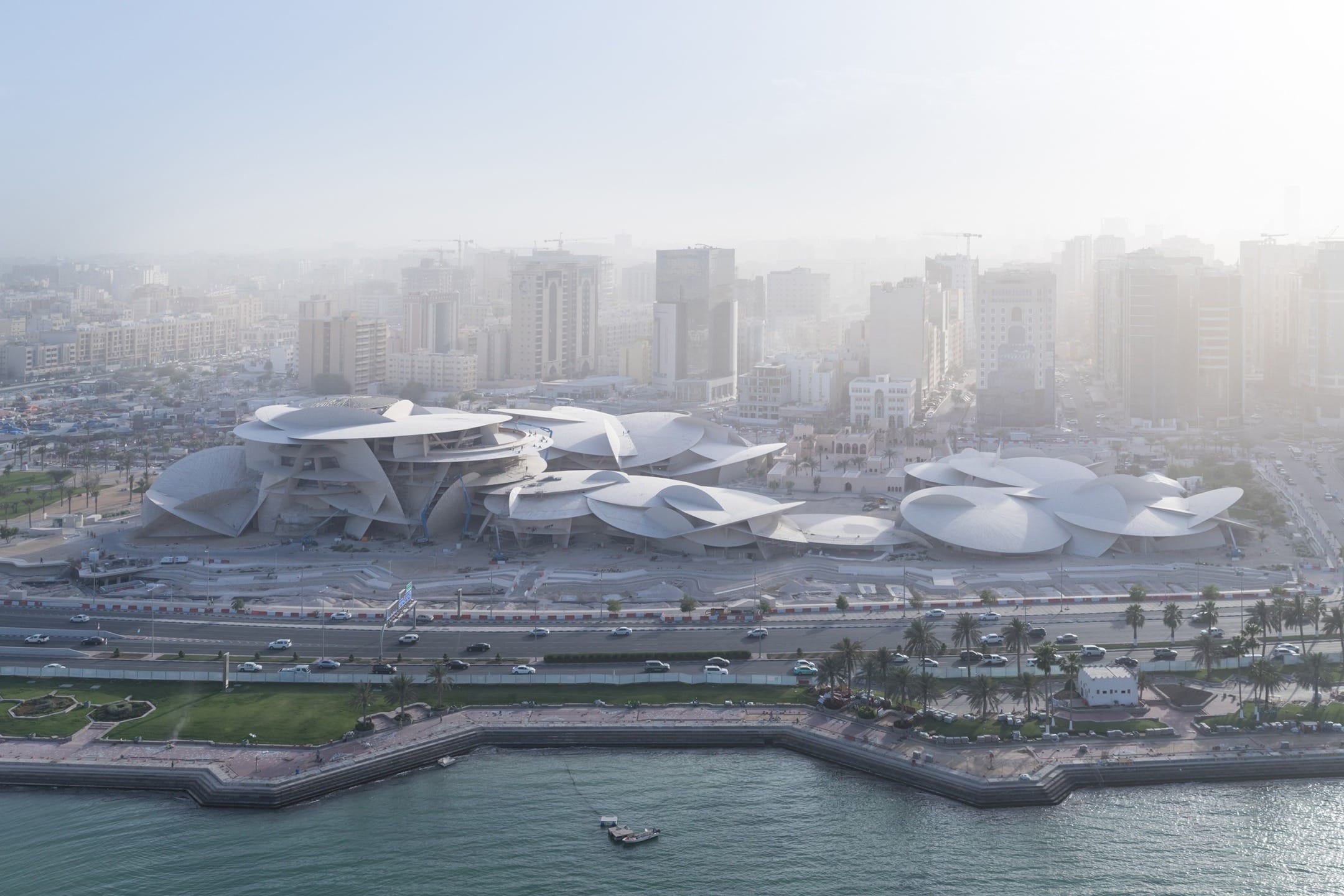 Aerial view of a modern architectural museum with unique overlapping disk-shaped roofs in an urban landscape.