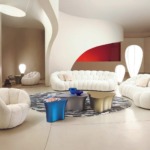 Modern living room with white sofas, unique tables, and artistic lighting in a spacious, minimalist setting.