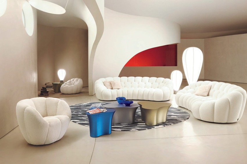 Modern living room with white sofas, unique tables, and artistic lighting in a spacious, minimalist setting.