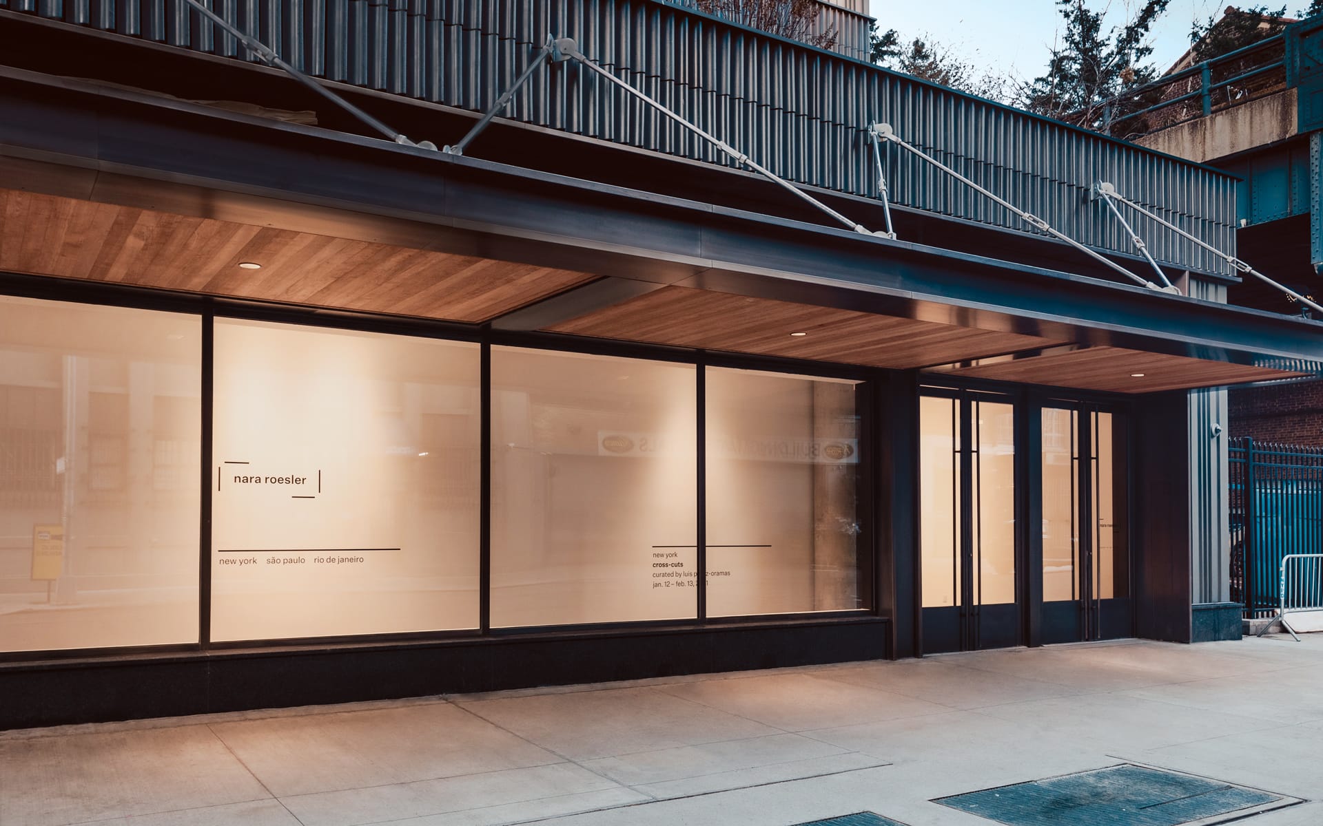 Street view of an art gallery with large windows and minimal signage on a quiet urban sidewalk.