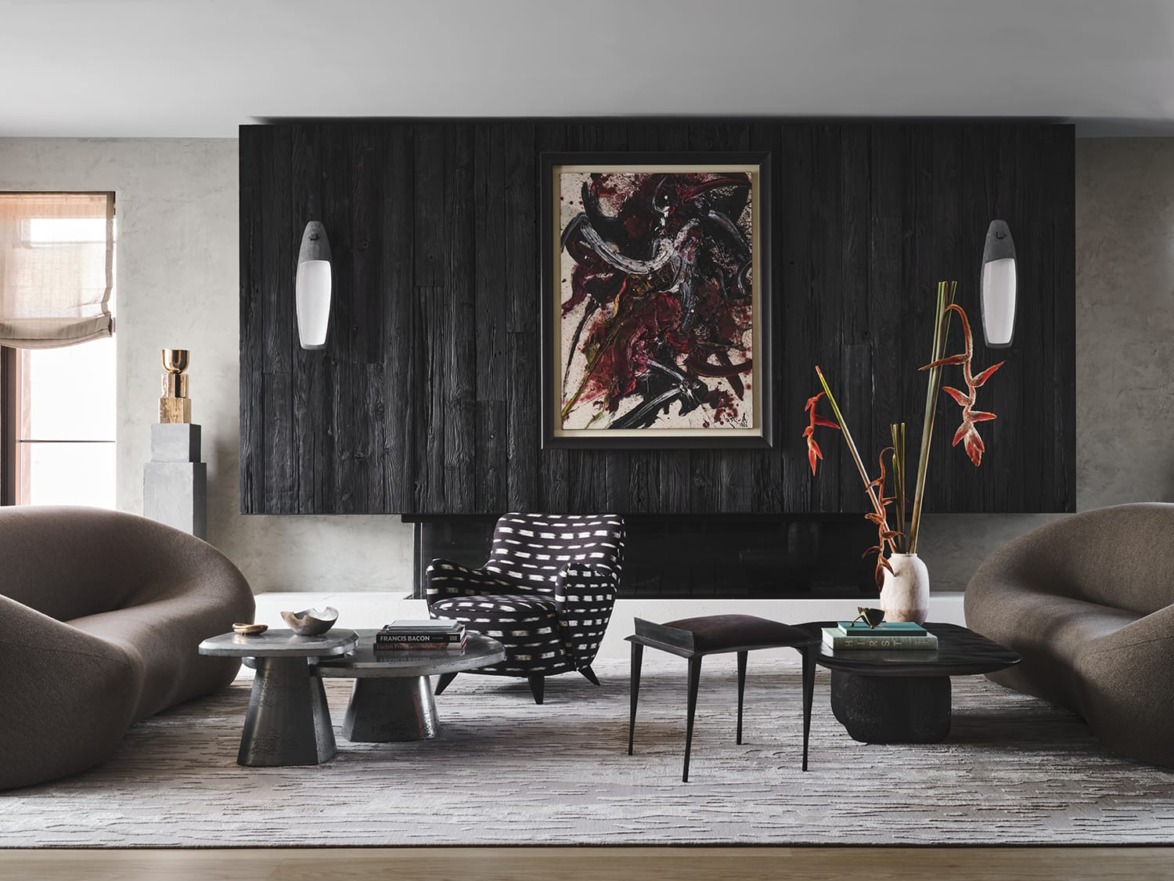 Modern living room with dark accent wall, abstract art, contemporary furniture, and decorative plants.