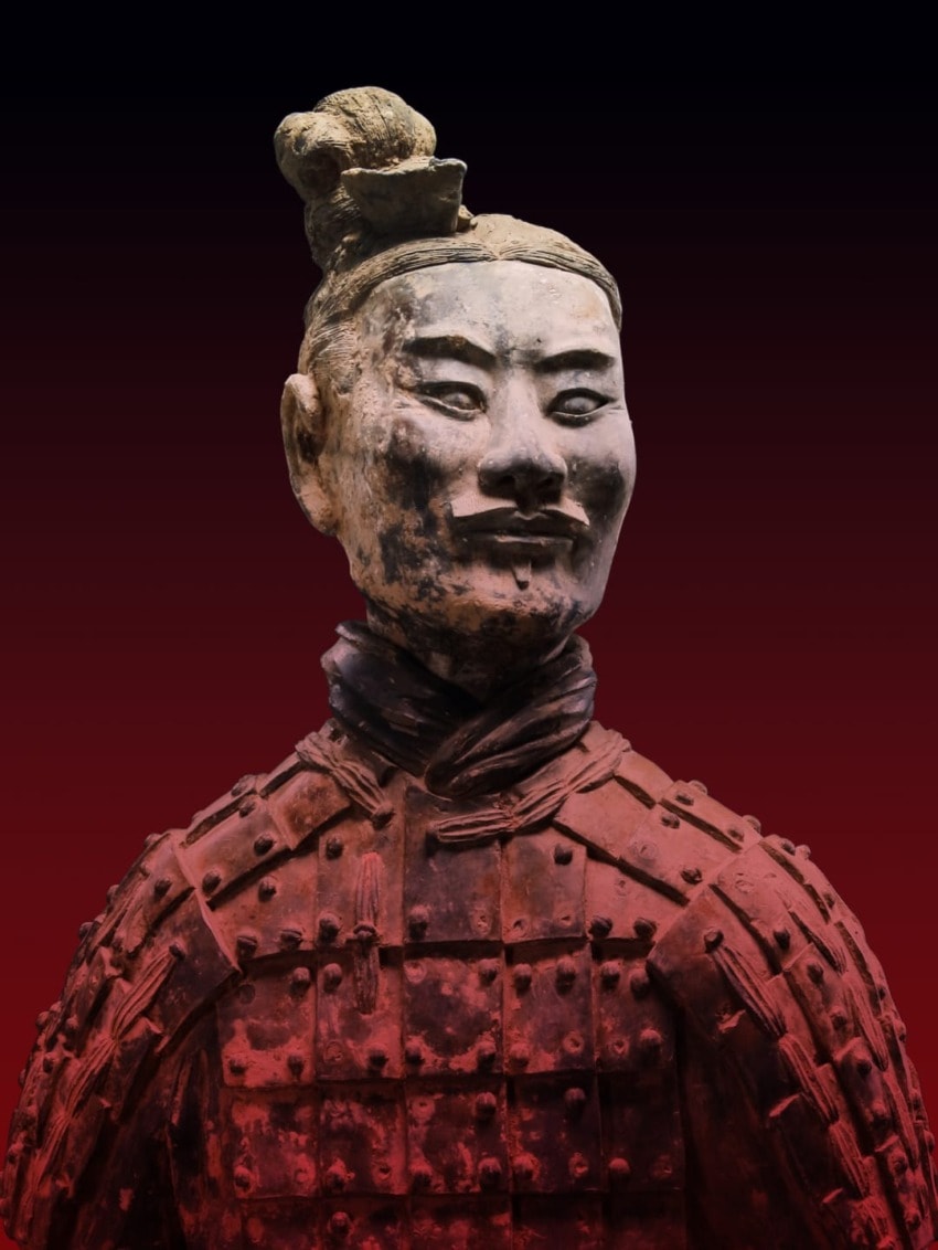 Terracotta Warrior statue from China's Qin Dynasty, close-up showing detailed armor and facial features against dark background