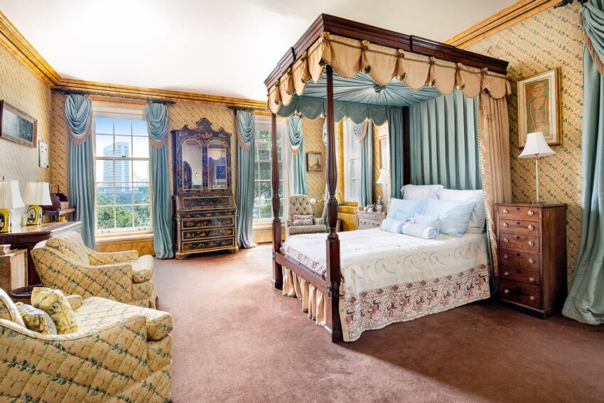 Elegant bedroom with a four-poster bed, vintage furniture, patterned wallpaper, and large window with a view.