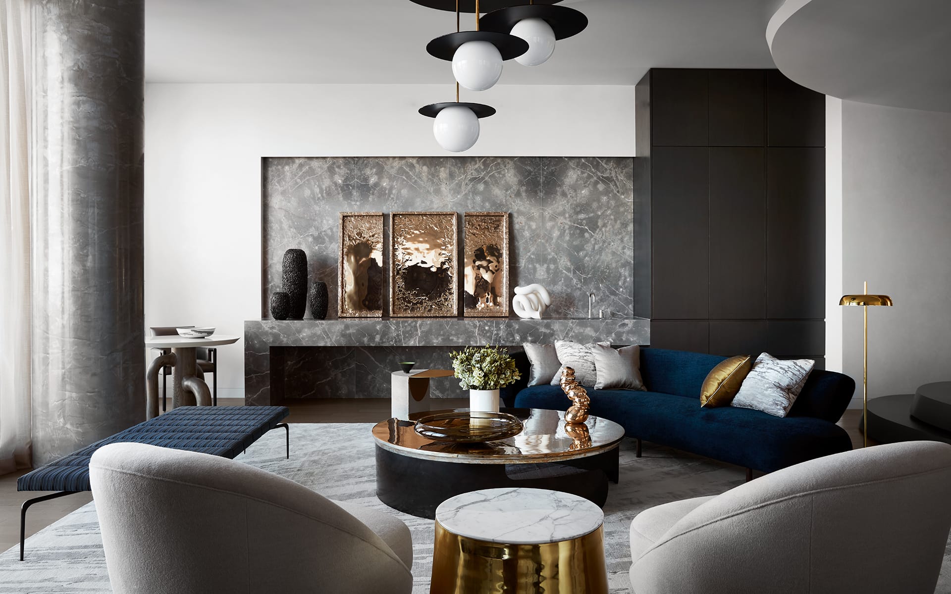 Modern living room with blue sofa, round coffee table, abstract art, and contemporary lighting fixtures.